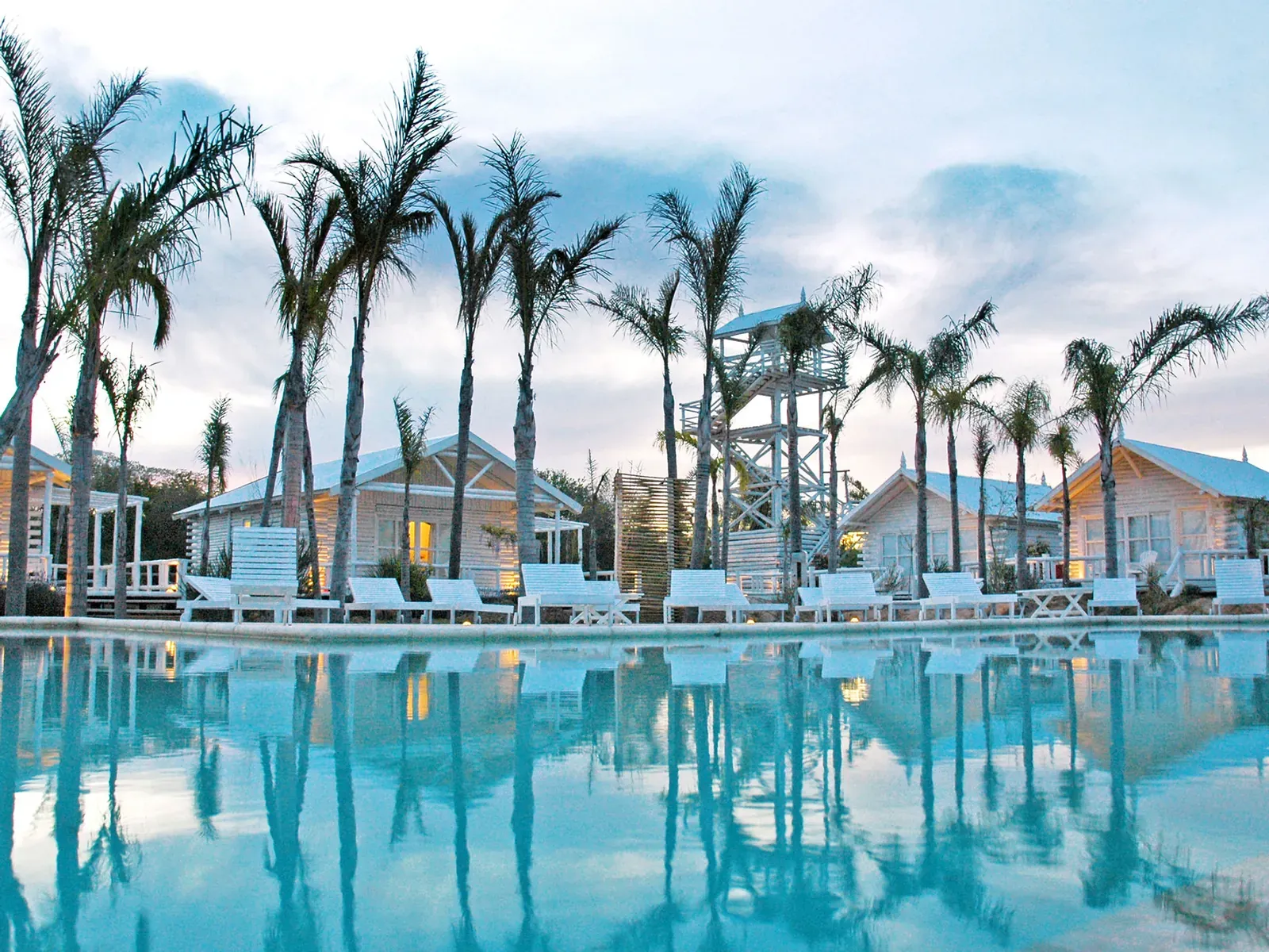 Piscina rodeada de palmeras al atardecer